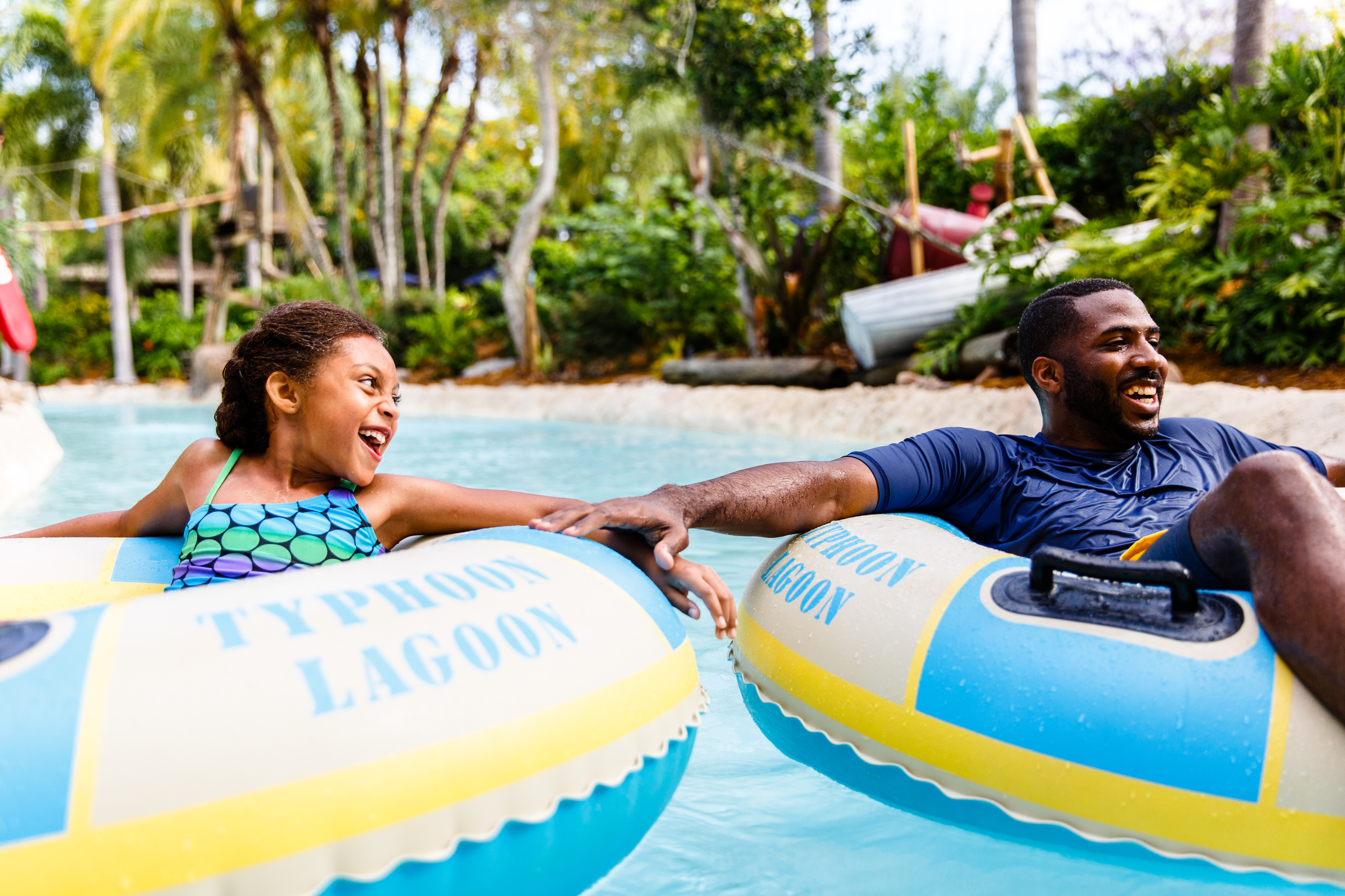 Father and daughter holding onto each other's lazy river tube as they float down the lazy river at Disney's Typhoon Lagoon Water Park.