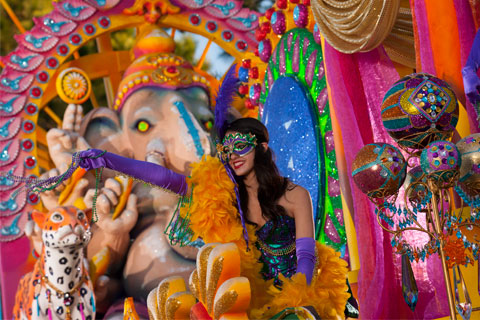 Female decorated in colorful Mardi Gras attire on a colorful Mardi Gras float featuring a fake elephant and leopard for Universal Orlando Resort's Mardi Gras parade.