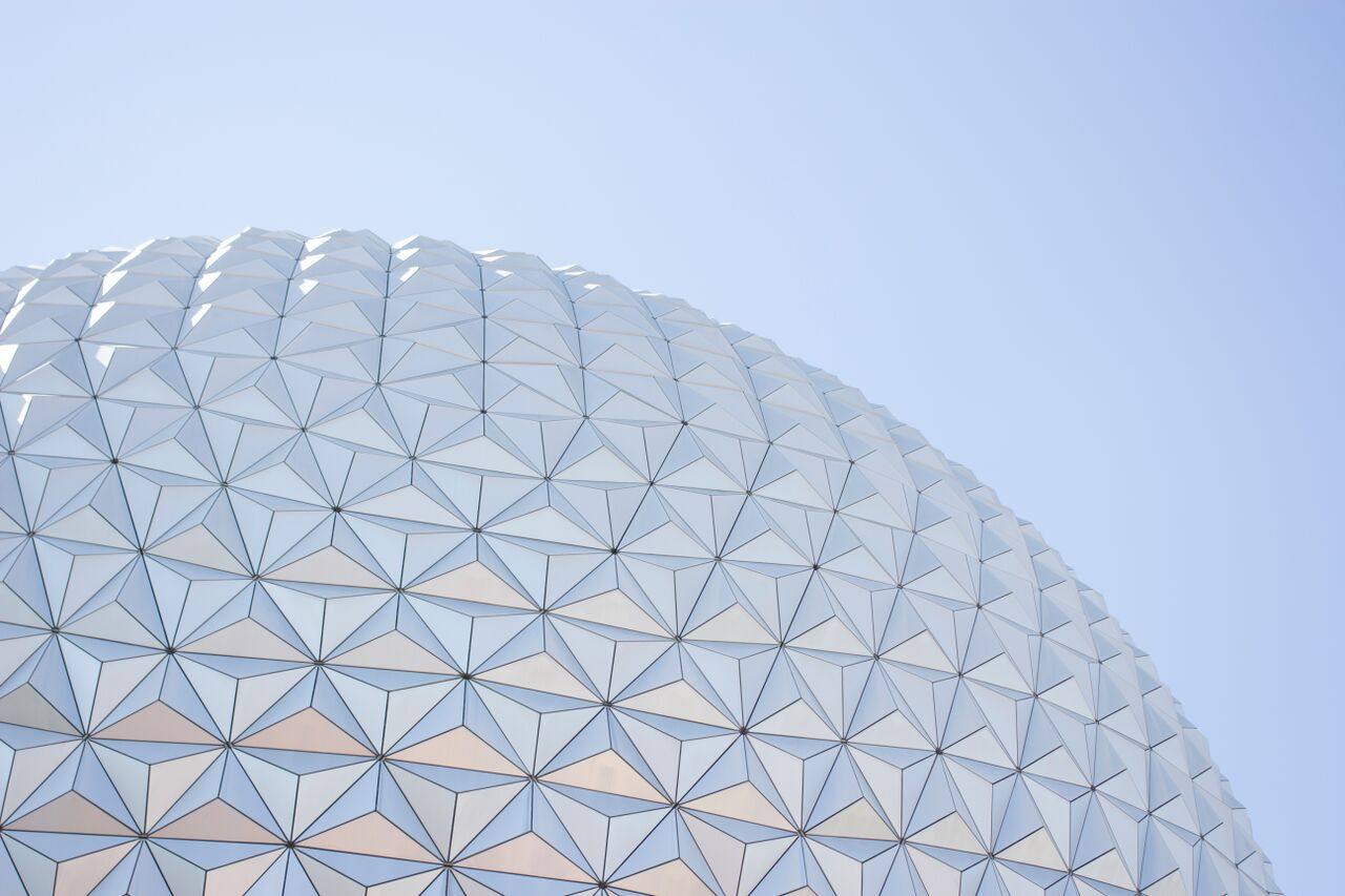Close-up shot of an up-looking angle of the Epcot ball during the daytime, clear, blue skies. Photo credit to https://tayloratdisney.com