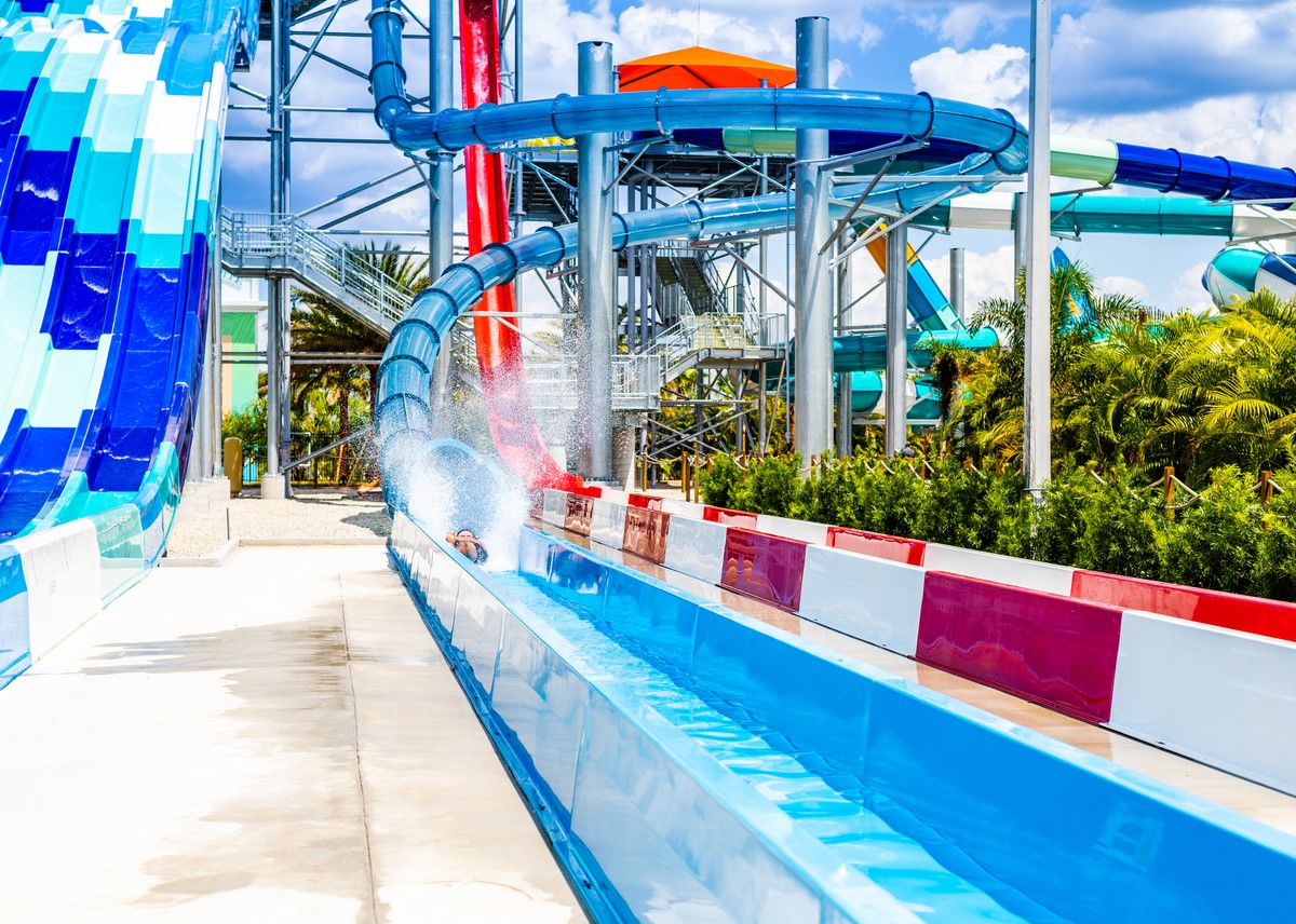 Person reaching end of blue close-tubed slide at Island H2O Live! during the daytime.