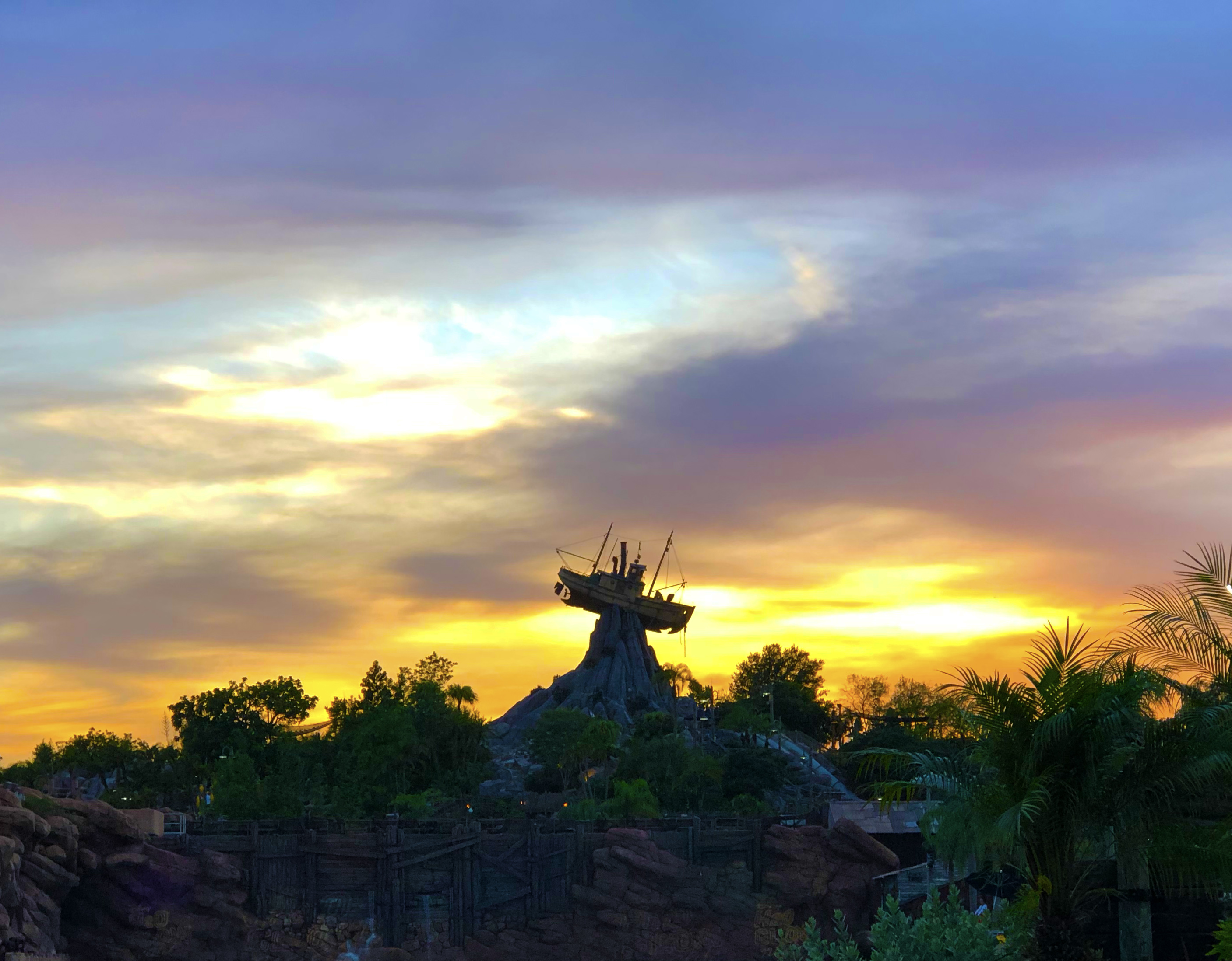 Disney's Typhoon Lagoon shipwreck focal point atop a hill overlooking the sunset.