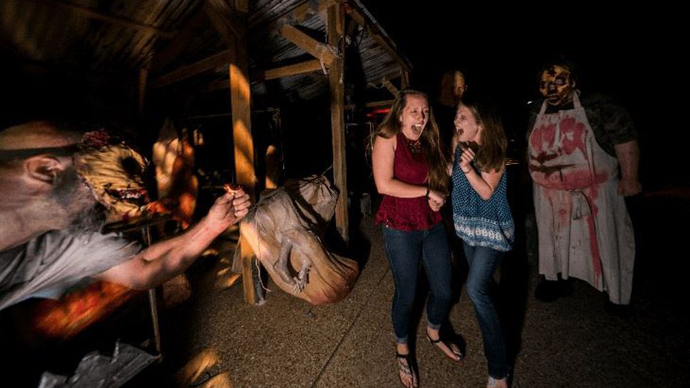 Scare actors (one on left, one on right) coming toward two female guests who are screaming in fear at Busch Gardens Howl-O-Scream, Tampa Bay, Florida.