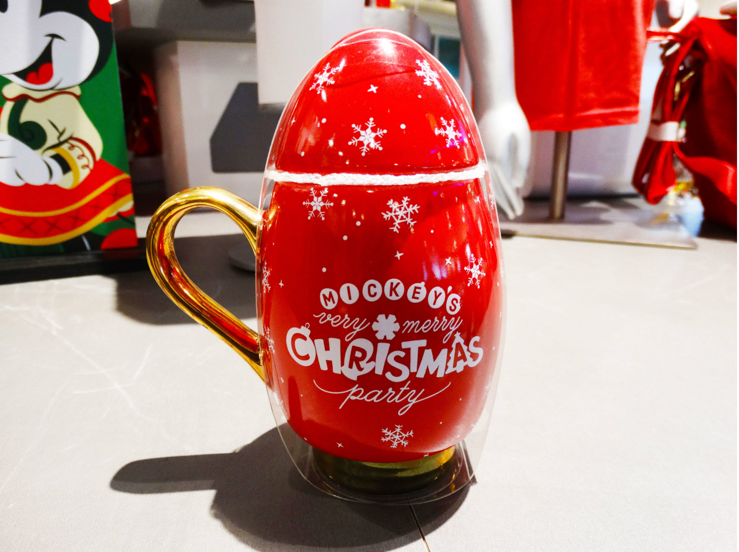 Backside of Mickey's Very Merry Christmas Party mug sitting on shelf in a store at the Magic Kingdom® Park. Reads the name of the event and has snowflakes all over the mug.Lake Buena Vista, Florida.