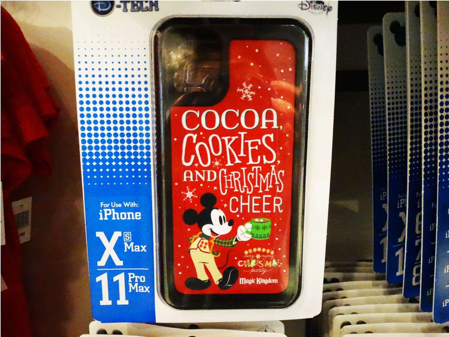 Limited release iPhone case that reads "Cocoa, Cookies, and Christmas Cheer" on red background with snowflakes and Mickey Mouse holding a cup off cocoa on the bottom left corner. Name of event, Mickey's Very Merry Christmas Party, Magic Kingdom®" printed on the bottom right. Lake Buena Vista, Florida, 2019.