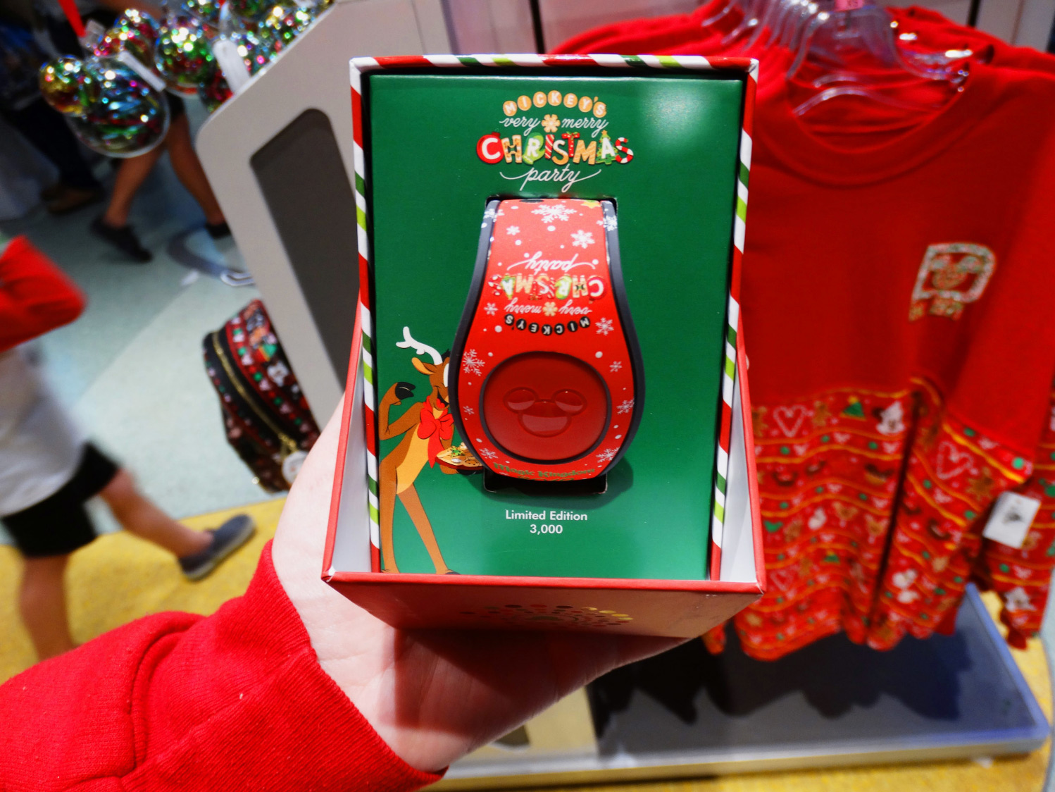 Close shot of hand holding the limited edition of Mickey's Very Merry Christmas Party red Magic Band at the Magic Kingdom® Park, Walt Disney World® Resort, Lake Buena Vista, Florida.