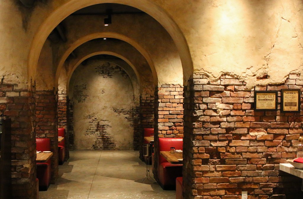The "tunnel of love" hallway that features brick walls and booths on both sides of the hallway. Enzo's Hideaway Tunnel Bar at Disney Springs, Lake Buena Vista, Florida.