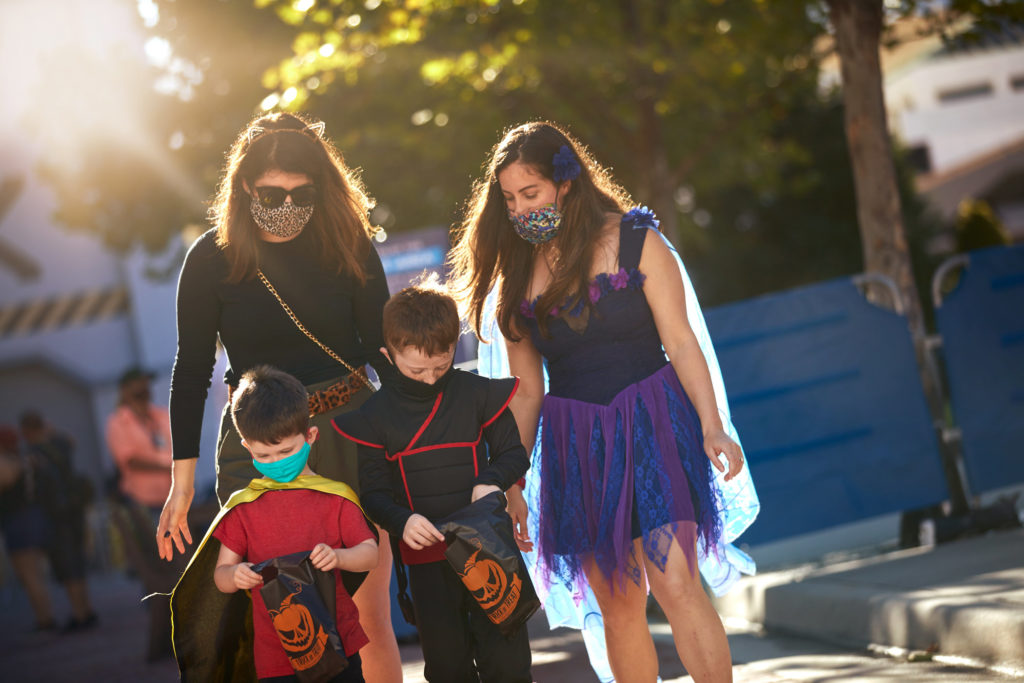 Daytime photo of two women walking with two small children (boys) in front of them as they're all dressed in Halloween costumes at Universal Orlando Resort's Halloween Seasonal Experience. 2020.
