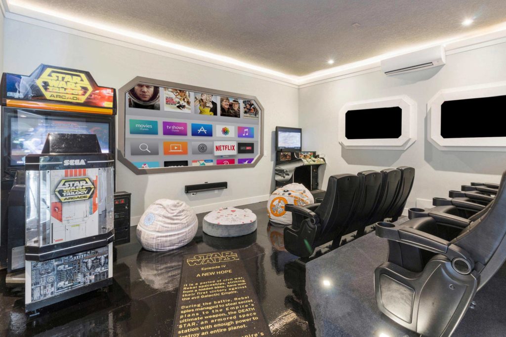 Galaxy-inspired theater room with Star Wars Arcade game (left), bean bag chairs, and theater-style recliner seating at Designed for Vacation (RVH_320M) at Reunion Resort. Kissimmee, Florida.